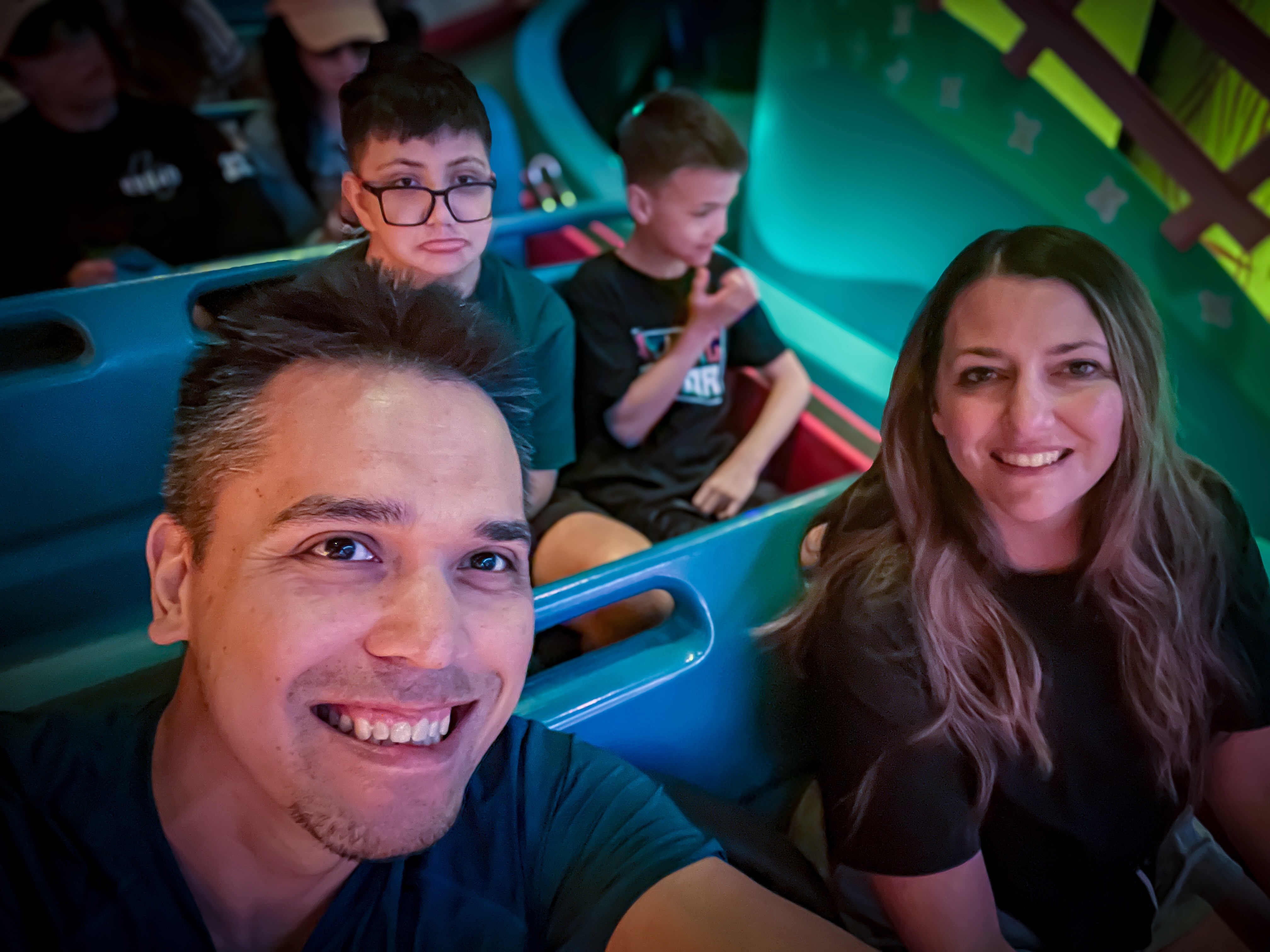 Jason with his family seated together on a colorful ride.