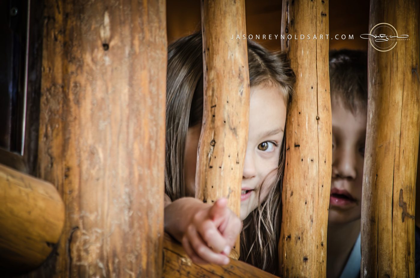 Children Peeking Through Log Railing