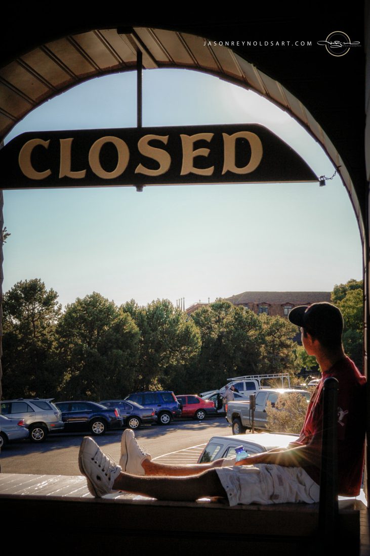 CLOSED Sign Framing a Seated Young Man