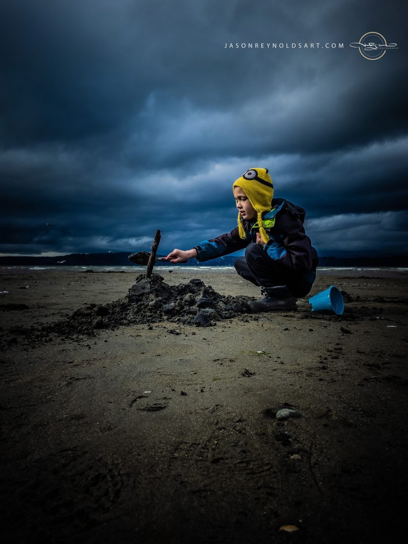 Federal Way beach — child building sand mound under stormy sky