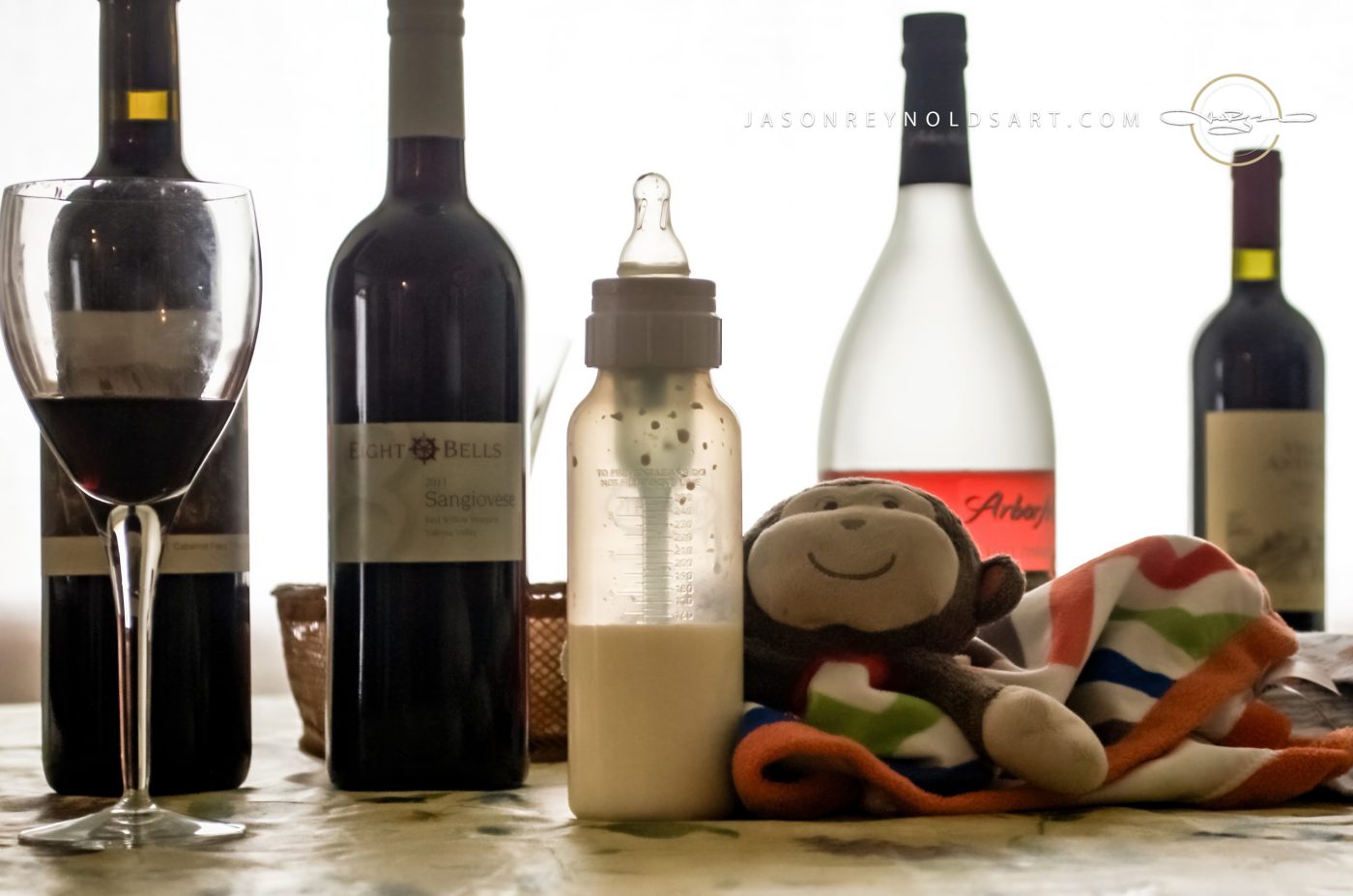Still life with wine bottles, baby bottle and stuffed monkey