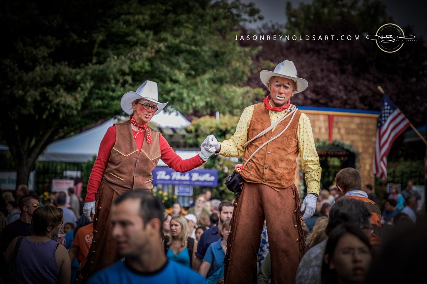 Stilt-walking cowboys entertaining a crowded outdoor fair